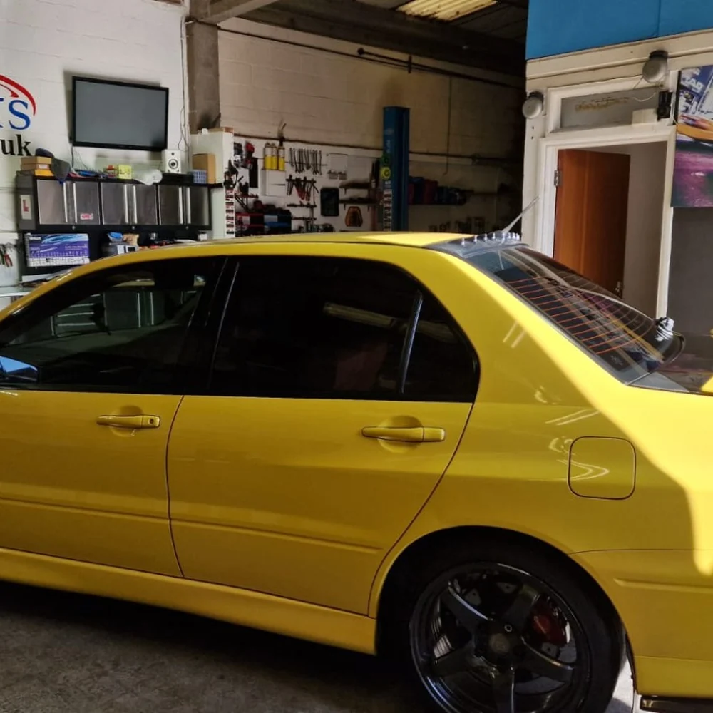Yellow Mitsubishi Evo with dark window tinting inside the Valu Tints workshop